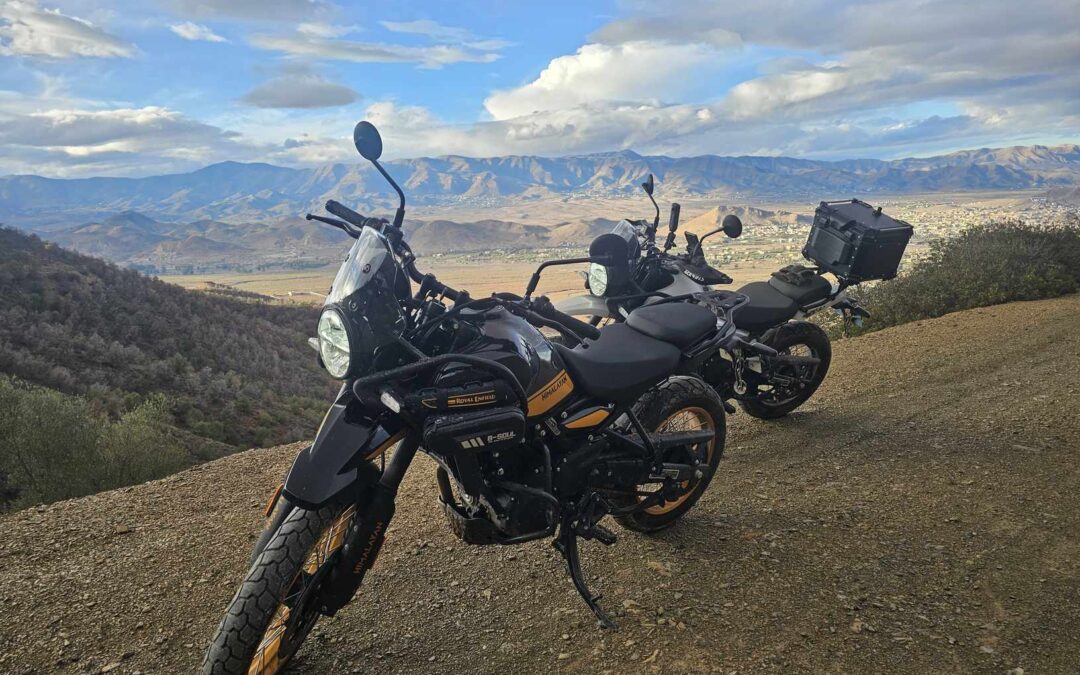 Twee adventuremotoren op een grindpad met uitzicht over een vallei en bergketen
